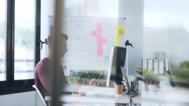 Modern bir ofiste bilgisayarla çalışırken akıllı telefonlu mesajlar gönderen yakışıklı girişimci videosu.