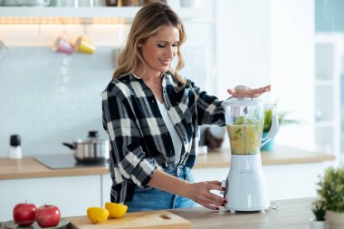 Evde, mutfakta taze kahvaltı için meyve karıştıran olgun bir kadın resmi..