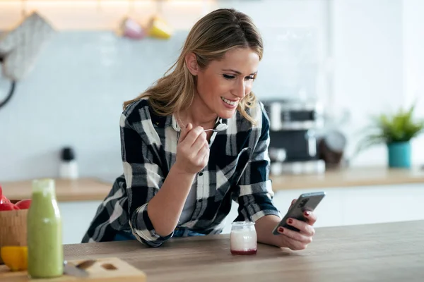 Shot Beautiful Mature Woman Eating Yogurt While Sending Messages Smartphone — Stock Photo, Image