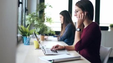 İki genç iş kadınının bilgisayarla çalışırken evde kulaklık takıp müşterilerle konuştuğu video..