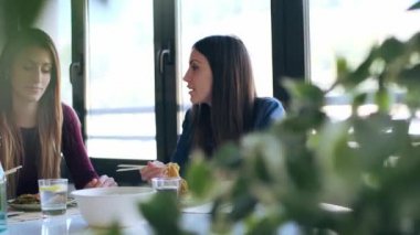 Gülümseyen iki güzel kadının videosu. Japon yemeklerini yerken evdeki mutfakta birbirlerine bakıyorlar..