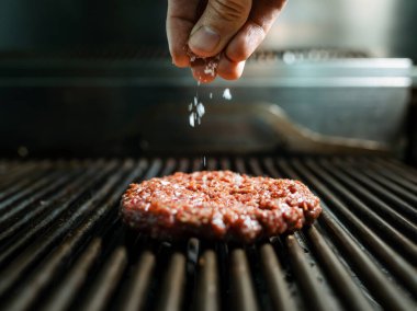 Lokanta mutfağında ızgarada leziz bir burger hazırlayan el aşçısı..