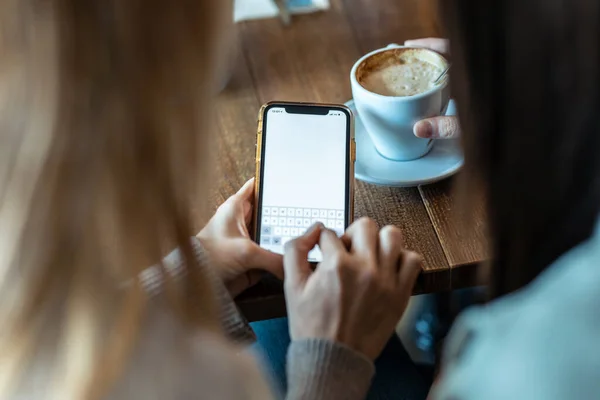 Skjuten Två Vackra Kvinnor Vänner Dricka Medan Ser Smart Telefon — Stockfoto