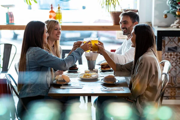 レストランで楽しい時間を過ごしながら ビールで乾杯する幸せな若い友人グループのショット — ストック写真