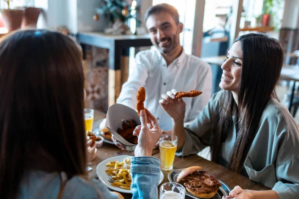 Tiro Jovens Amigos Atraentes Grupo Comer Hambúrgueres Enquanto Conversa Divertindo — Fotografia de Stock