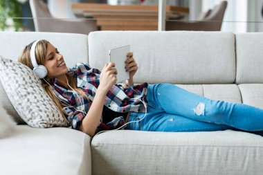 Güzel genç bir kadının dijital tabletle görüntülü konuşma yaparken evinde kanepede yatan arkadaşına bir şey açıklarken çekilmesi..