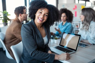 Ofiste yeni projelerinden bahsederken dizüstü bilgisayarlarla çalışan çok yönlü iş adamlarının fotoğrafları..