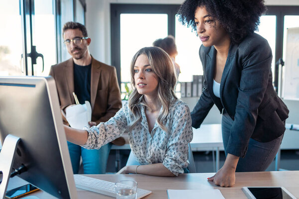 Shot of successful business multiage team standing around computer for presentation of work in the coworking space.