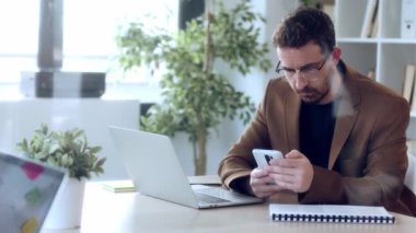 Evde bazı belgeleri okurken bilgisayarla çalışan kendinden emin bir yetişkinin videosu..
