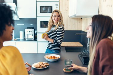 Üç zeki girişimci kadının dinlenirken konuştuğu ve birlikte çalıştıkları yerdeki mutfakta kahvaltı ettikleri bir fotoğraf..