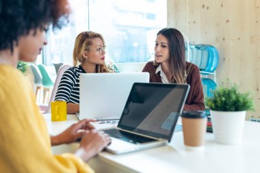 Birlikte çalıştıkları yerde dizüstü bilgisayarlarla çalışan çok ırklı iş kadınlarının yeni projelerinden bahsederken çekilmiş..