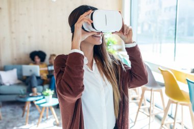Modern genç girişimci kadının sanal gerçeklik kulaklığı takıp birlikte çalışma alanının keyfini çıkarırken çekilmiş..