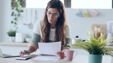 Evdeki mutfakta donut yerken dizüstü bilgisayarından gülümseyen genç bir kadının videosu..