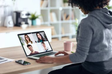 Afro iş kadınının evdeki mutfaktaki dizüstü bilgisayarla görüntülü konuşma yapması..