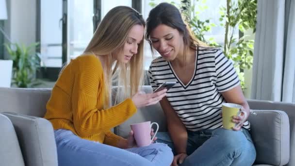 Video Dos Mujeres Jóvenes Sonrientes Hablando Mientras Miran Teléfono Inteligente — Vídeos de Stock