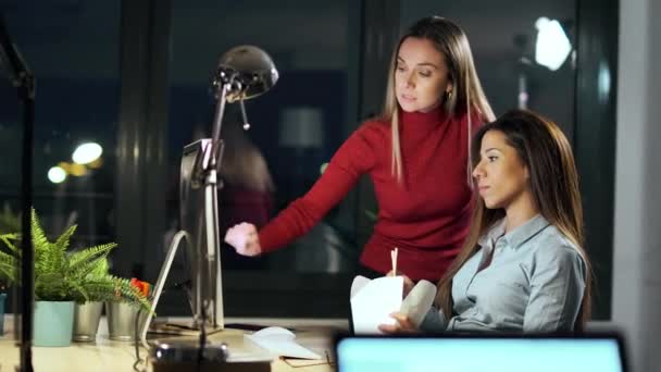 两名聪明的女商人晚上在办公室聊天时与笔记本电脑一起工作的视频 — 图库视频影像