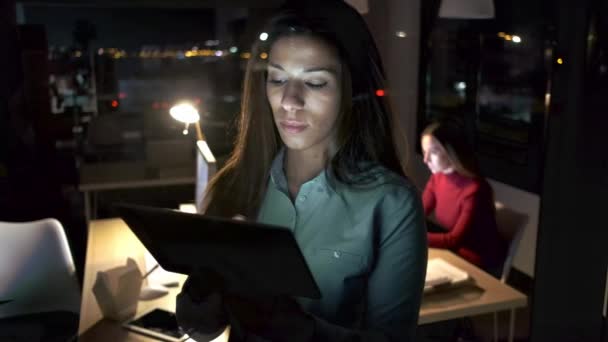 夜にオフィスに立って彼女のデジタルタブレットを取りながら休憩を取るスマートかなりビジネス女性のビデオ — ストック動画