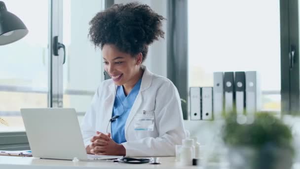 診察中にノートパソコンとのビデオ通話を通じて患者に医療を説明しながら話す魅力的なアフロ女性医師のビデオ — ストック動画