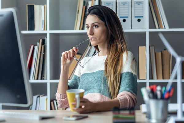 現代のスタートアップオフィスでコーヒーを飲みながらコンピュータで働く濃縮若いビジネス女性のショット — ストック写真