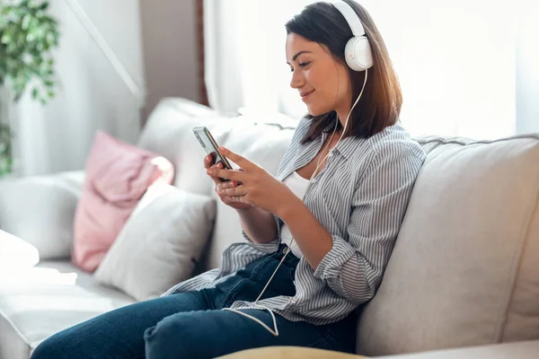 Tiro Mujer Joven Sonriente Escuchando Música Con Teléfono Inteligente Mientras —  Fotos de Stock