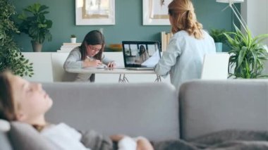 Yetişkin bir annenin, hasta kızına evde bakarken genç bir bayan doktorla görüntülü konuşma yaptığı bir video..