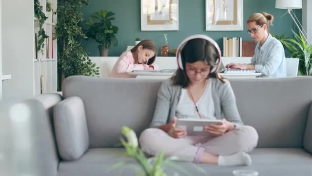 小女孩在家里客厅里用数码平板电脑听音乐的视频 — 图库视频影像