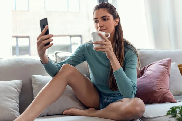 Tiro Mujer Sonriente Bastante Joven Usando Teléfono Móvil Mientras Bebe —  Fotos de Stock