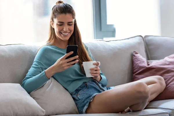 Tiro Mujer Sonriente Bastante Joven Usando Teléfono Móvil Mientras Bebe —  Fotos de Stock