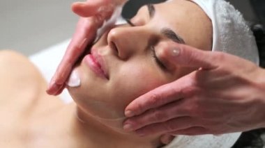 Kozmetik uzmanının, spa merkezinde bir sedyede yatarken kadınlara yüz masajı yaptığı bir video..