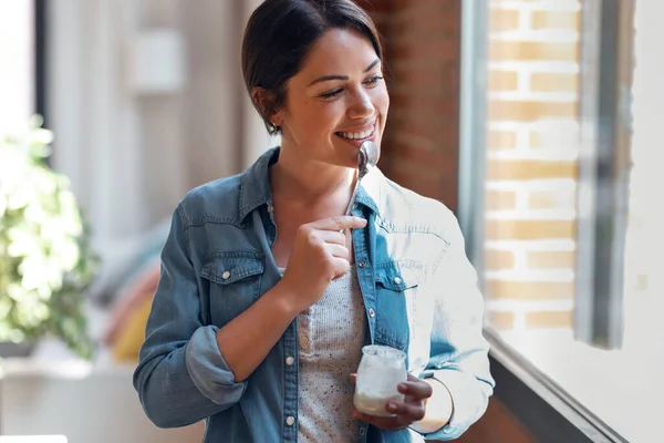 Girato Felice Bella Donna Mangiare Yogurt Mentre Piedi Soggiorno Casa — Foto Stock