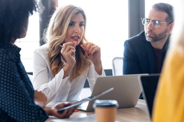 Modern başlangıçta yeni projelerinden bahsederken dizüstü bilgisayarlarla çalışan çok yönlü iş adamlarının fotoğrafları..