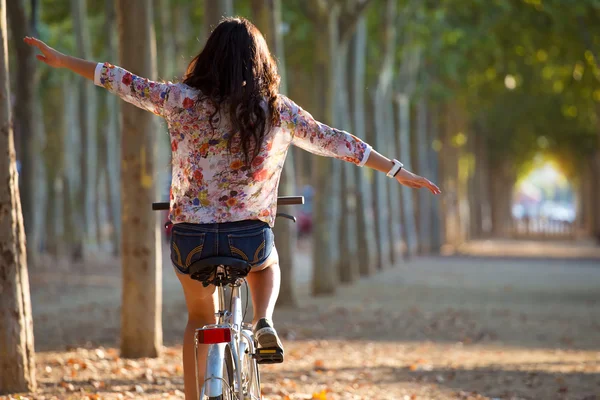 Bella ragazza in sella alla bicicletta in una foresta . — Foto Stock