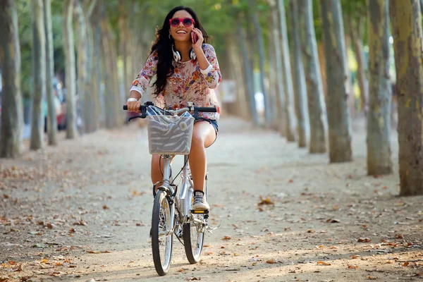 Menina bonita andar de bicicleta e falar ao telefone . — Fotografia de Stock
