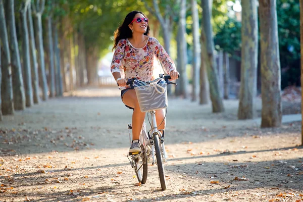 Bella ragazza in sella alla bicicletta in una foresta . — Foto Stock