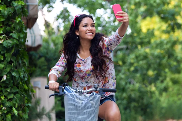 Hübsches junges Mädchen fährt Fahrrad und macht ein Selfie. — Stockfoto