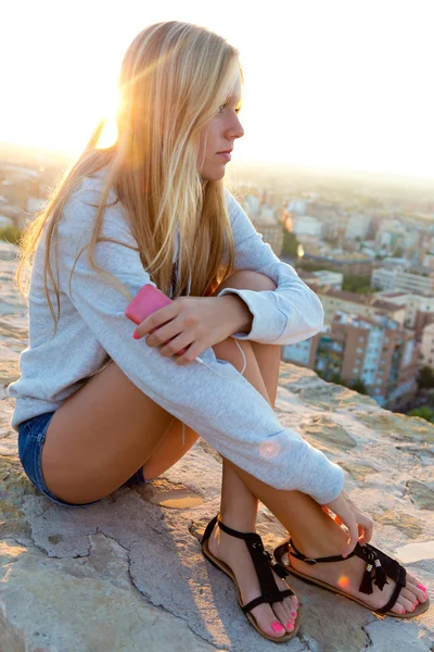 Vacker flicka sitter på taket och lyssna på musik. — Stock fotografie