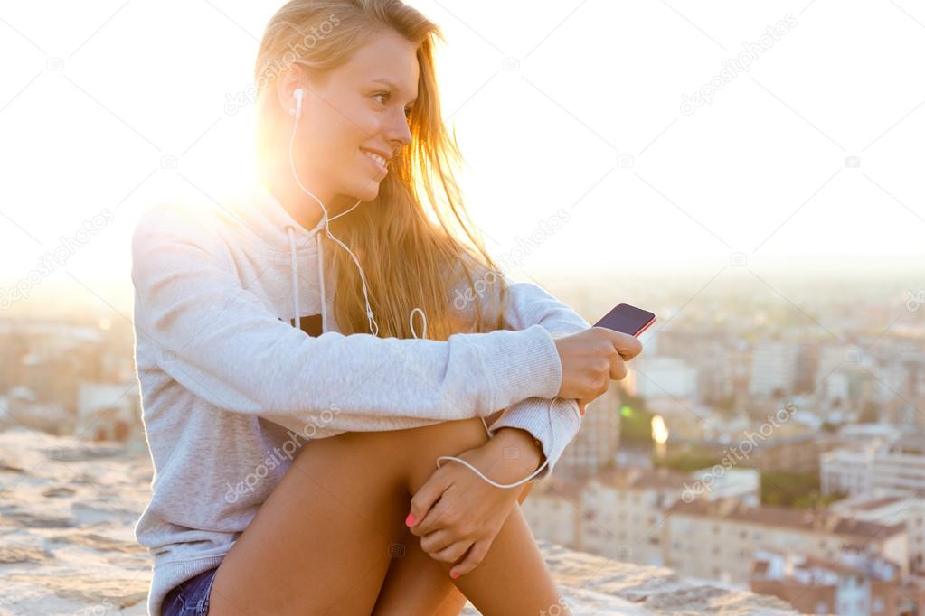 Beautiful girl sitting on the roof and listening to music.