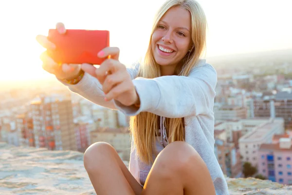 Mooie blonde meisje dat neemt een selfie op het dak. — Stockfoto