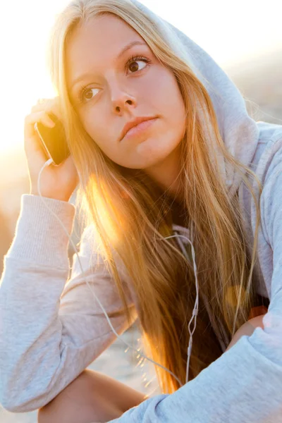 Vacker flicka sitter på taket och lyssna på musik. Stockbild