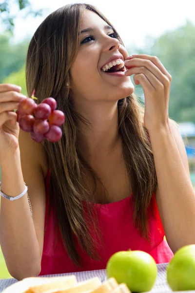 Jovem garota comendo uvas em piquenique romântico no campo . — Fotografia de Stock