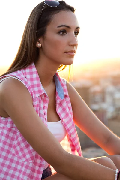 Menina bonita sentada no telhado ao pôr do sol . — Fotografia de Stock