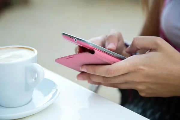 Vacker flicka dricka kaffe och textilen med mobiltelefon. — Stockfoto