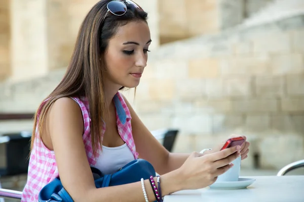 Mooi meisje, drinken koffie en texting met mobiele telefoon. — Stockfoto