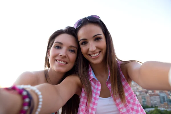 Beautiful girls taking a selfie on the roof at sunset. — Stock Photo, Image