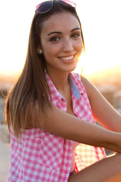 Pretty girl sitting on the roof at sunset. Stock Image