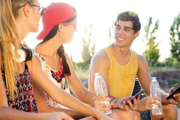 Groupe d'amis textos avec leurs téléphones intelligents dans le parc . — Photo