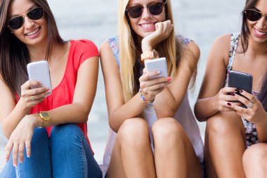 Üç kız parkta onların akıllı telefonlar ile sohbet 