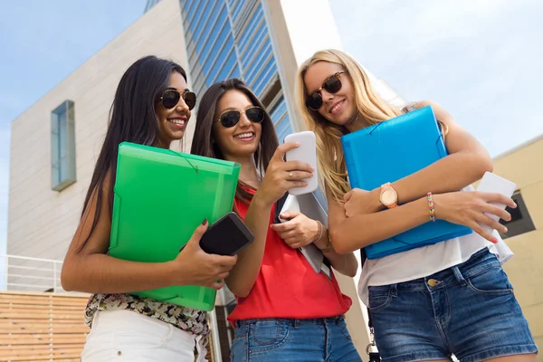 Tres chicas charlando con sus teléfonos inteligentes en el parque —  Fotos de Stock