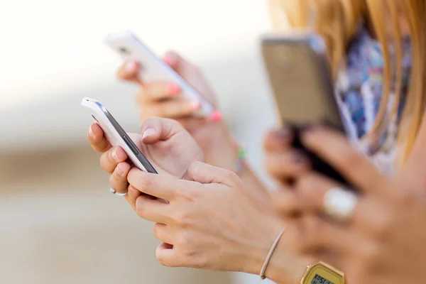 Tres chicas charlando con sus teléfonos inteligentes en el parque —  Fotos de Stock