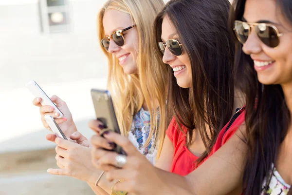 Três meninas conversando com seus smartphones no parque — Fotografia de Stock